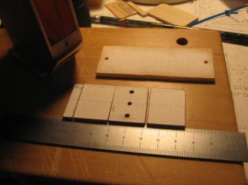 03-23-14: This shows the hatch, one piece of 1/8" balsa, and the top,
made from four pieces.&nbsp; The four pieces of the top are, from left
to right, 1/8" ply, 1/8" balsa, 1/8" ply, and 1/8" balsa.<br><br>

All of these pieces show computer paper bonded (with 3M General Purpose
45 spray adehesive) to the top side.&nbsp; I experimented with this new
way (new to me) of building.&nbsp; I made plans for all the parts on my
computer.&nbsp; (I used free software called Xfig on a Slackware Linux
based computer.)&nbsp; When I had parts to cut or drill I printed the
plan and glued it to the wood with the spray adhesive.&nbsp; Then I
drilled on the marked centers or I cut beyond the marked edge, then
sanded down to the edge.&nbsp; This helped, but I still found I had to
use great care when drilling holes or shaping a part.&nbsp; It helped
to make an indentation with a center punch before drilling a
hole.&nbsp; And I went slowly when shaping a part.&nbsp; It helped to
use calipers to check the dimensions periodically when sanding down to
a line.<br><br>

The top was a nasty part to sand.&nbsp; Assembling it from the four
pieces was easy enough, but sanding the edges round, after it was glued
to the top of the pod assembly, was difficult.&nbsp; The alternating
hard and soft of the plywood and balsa was hard to sand to a uniform
shape.&nbsp; If I build another one of these I may make some changes to
avoid this problem.<br><br>

I should explain that I bought a new tool, a Two-speed Dremel motor
tool and a Dremel drill press.& The two work together and are in some
of the pictures of this collage.&nbsp; They worked well with this new
way of building.&nbsp; I made much use these attachements:<br>

   <ul><li>various drill bits<br>
   <li>cylinderical sanders--good for shaping<br>
   <li>a cutter that looks a little like a drill bit, but cuts on its
   side--good for rough cutting<br>
   <li>the cut off wheel--good for cutting the bolts that mount the
   pod<br>
</ul>

By the way, the computer paper sanded off more readily if moistened it
a bit.&nbsp; I do recommend removing the paper, though.<br><br>

I need to explain the three holes in the top.&nbsp; Originally I
planned to run a wire tie through two of the holes and around the motor
to brace it against the top.&nbsp; The third hole was to help position
a pad that the motor would rest against.&nbsp; As I was building I
decided that the strap and pad were not needed, so I kept the holes for
extra ventillation.